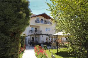 a white building with a balcony and a bird in a yard at Pension Lale in Peštani