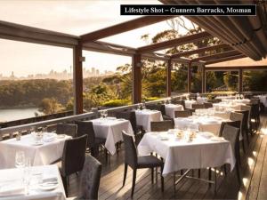 een restaurant met witte tafels en stoelen op een terras bij BOT01 - Balmoral Light and Airy Beach Apartment in Sydney