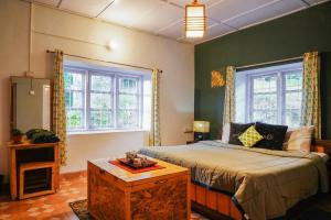 a bedroom with a bed and two windows at De Huts Kodaikanal in Kodaikānāl