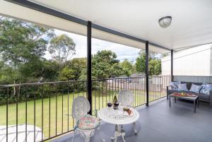 a screened in porch with a table and chairs at Little Bank House in Mount Tamborine