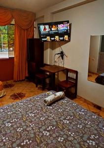 a bedroom with a bed and a tv on the wall at HOSPEDAJE EL CANTARO in Tingo María