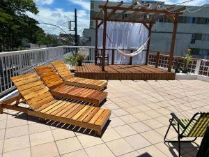 2 Holzstühle und ein Pavillon auf einer Terrasse in der Unterkunft 8 Quarto Cama Queen e SmartTv Netflix in Itajaí