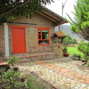 a small brick house with a red door at Encanto - Habitación con baño privado in Villa de Leyva