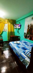 a bedroom with a bed and a tv on the wall at HOSPEDAJE EL CANTARO in Tingo María