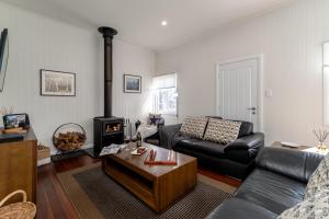 sala de estar con sofá y estufa de leña en Bank House Tamborine Mountain en Mount Tamborine