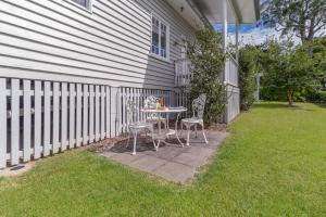 een patio met een tafel en stoelen naast een hek bij Bank House Tamborine Mountain in Mount Tamborine