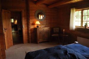 a bedroom with a bed and a mirror and a chair at Bjælkehuset på Harrild Hede in Brande