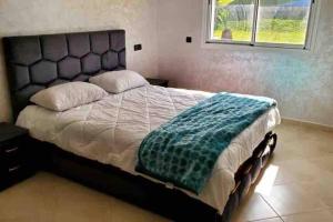 a bedroom with a bed with a blue blanket on it at New apartment with water view in El Jadida