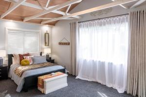 a bedroom with a bed and a large window at The Chefs Cottage in Waikanae