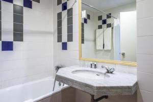 a bathroom with a sink and a mirror and a tub at Hotel Londres Estoril / Cascais in Estoril
