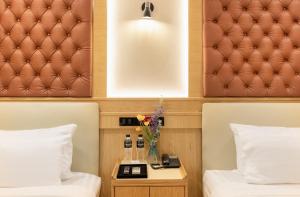 a hotel room with two beds and a table with flowers at Heaven Boutique Hotel in Bangkok