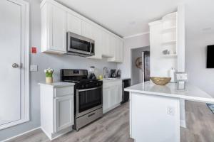 a kitchen with white cabinets and a stove top oven at Sleek 1 Bedroom Apartment Plus Balcony 30 Mins to NYC in New Rochelle