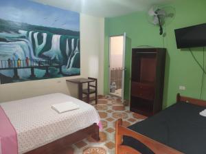 a bedroom with a bed and a painting on the wall at HOSPEDAJE EL CANTARO in Tingo María