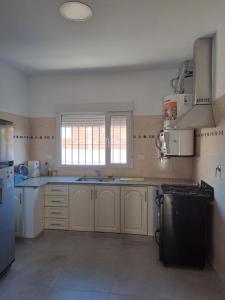 a kitchen with white cabinets and a black refrigerator at Departamento RAWSON CALLE MITRE 956 in Rawson