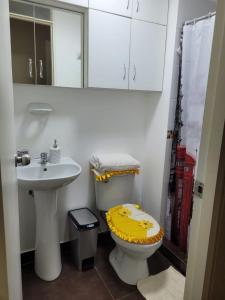 ein Badezimmer mit einem Waschbecken und einem WC mit einem gelben Deckel in der Unterkunft Departamento familiar in Lima