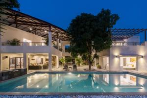 uma casa grande com uma piscina em frente em The Leaf by StayVista - An enchanting escape offering a pool, terrace, lush lawn, contemporary interiors, and indoor games em Alibaug