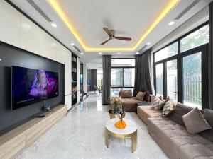 ein Wohnzimmer mit einem Sofa und einem Flachbild-TV in der Unterkunft Trippy villa: FLC Hạ Long in Hạ Long