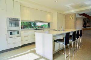 a kitchen with white cabinets and a counter with stools at Beach Haven in Point Lonsdale