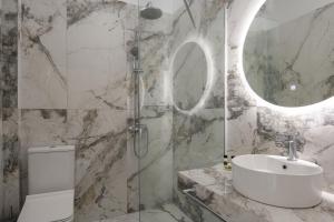 a bathroom with a sink and a shower with a mirror at VagAthan - Lux Holidays in Afitos