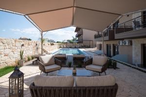 a patio with a couch and chairs and a pool at VagAthan - Lux Holidays in Afitos