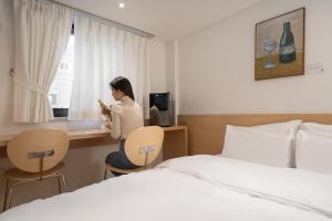 a woman sitting at a desk in a hotel room at Anook Hotel Guri in Guri