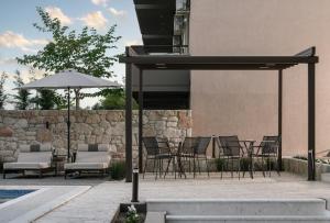 a patio with chairs and tables and an umbrella at VagAthan - Lux Holidays in Afitos