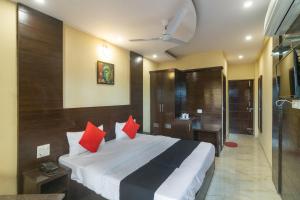 1 dormitorio con 1 cama grande con almohadas rojas en Capital O Hotel Rudraksh en Mājra