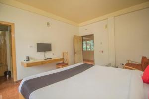een slaapkamer met een groot wit bed en een televisie bij Flagship 43145 Mayaban Resort in Ingrāj Bāzār