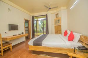 Schlafzimmer mit einem Bett, einem Schreibtisch und einem TV in der Unterkunft Flagship 43145 Mayaban Resort in Ingrāj Bāzār