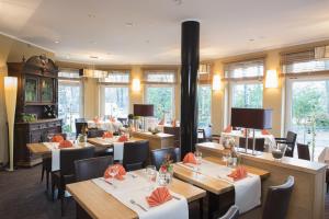 een restaurant met houten tafels, stoelen en ramen bij Hotel Meiners in Kirchhatten