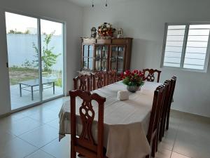a dining room with a table with flowers on it at Casa Flor de Mayo, fresca, climas, en privada in Mérida
