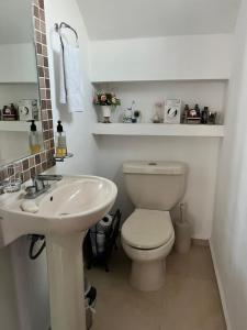 a bathroom with a white toilet and a sink at Casa Flor de Mayo, fresca, climas, en privada in Mérida