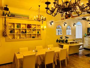 恩納村にあるオーベルジュ ボヌ シェール ラウーの黄色の壁とテーブル、シャンデリアが備わるダイニングルーム