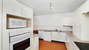a kitchen with white cabinets and a microwave at Terrigal Bay #9 Pool In Complex, Close To Beach Accom Holidays in Terrigal