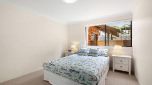 a white bedroom with a bed and a window at Terrigal Bay #9 Pool In Complex, Close To Beach Accom Holidays in Terrigal