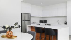 a kitchen with a white counter and a table and chairs at #15 The Ash Apartments Close To Beach Accom Holidays in Terrigal