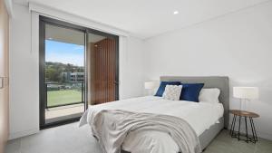 a white bedroom with a bed and a large window at #8 The Ash Apartments Close To Beach Accom Holidays in Terrigal