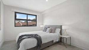 a white bedroom with a bed and a window at #8 The Ash Apartments Close To Beach Accom Holidays in Terrigal