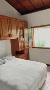 1 dormitorio con cama, armarios de madera y ventana en Refúgio Beira Mar, en Santa Cruz Cabrália