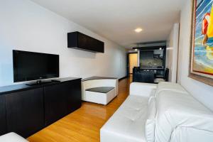 ein Wohnzimmer mit einem weißen Sofa und einem Flachbild-TV in der Unterkunft Departamento 3 dormitorios 2 baños, 2 TV, Piso Alto, República de El Salvador in Quito