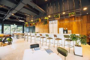 un restaurante con mesas blancas, sillas y plantas en Hotel BEGINS 倉箱蜜境文旅 en Keelung