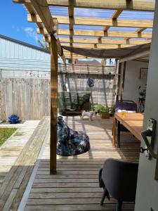 a wooden deck with a table and a wooden pergola at Home away from home air b and b in Whangarei