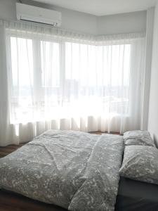 a bed in front of a window with white curtains at The Octagon Ipoh in Ipoh