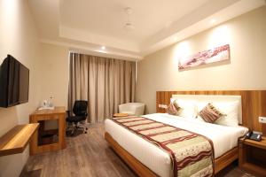 ein Hotelzimmer mit einem Bett, einem Schreibtisch und einem TV in der Unterkunft Hotel Le Roi Raipur at Raipur Railway Station in Raipur