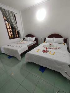 a bedroom with two beds with white sheets and two windows at DIỆP NGỌC MAI Guest House in Mui Ne