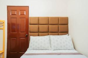 a bed with a brown headboard next to a door at Cozy BNB - Unit G in Batangas City