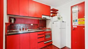 a red kitchen with a white refrigerator and red cabinets at Shamrock 8 in Mount Hotham +1 photo