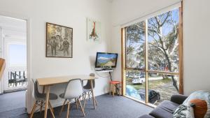 a living room with a table and a large window at Shamrock 8 in Mount Hotham
