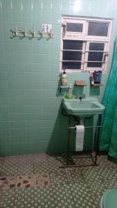 ein grünes Bad mit einem Waschbecken und einem Fenster in der Unterkunft Casa Martha in Ciudad Nezahualcóyotl