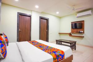een slaapkamer met een bed, een bureau en een televisie bij FabHotel Uday Vilas in Indore